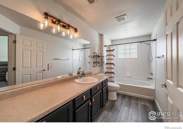 1004 Lucca Dr, Evans, CO 80620 - full bathroom with visible vents, toilet, shower / bathtub combination with curtain, vanity, and wood finished floors