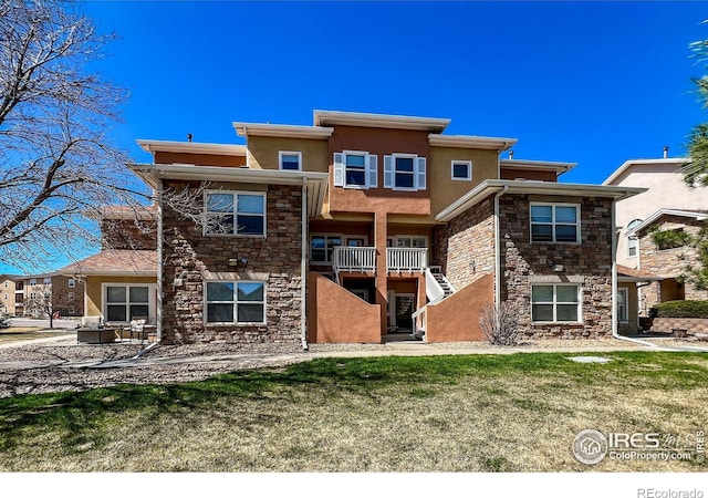 1004 Lucca Dr, Evans, CO 80620 - back of house with stairway, stucco siding, stone siding, and a lawn