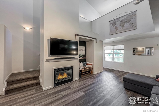 1004 Lucca Dr, Evans, CO 80620 - living room featuring a high ceiling, wood finished floors, baseboards, and a glass covered fireplace