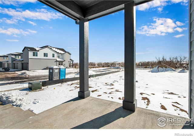 snow covered patio featuring a residential view