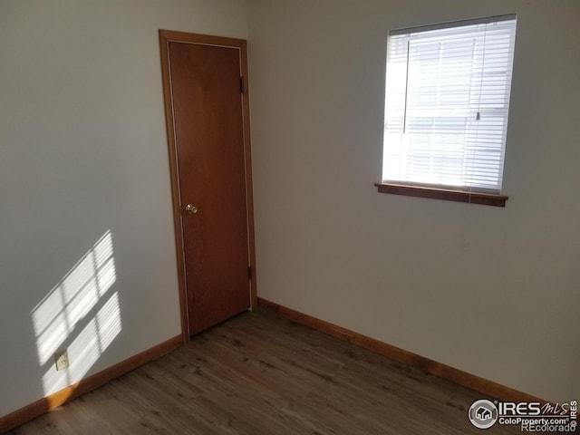 spare room with baseboards and wood finished floors