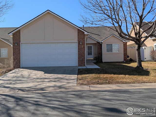 ranch-style house featuring driveway, brick siding, an attached garage, fence, and stucco siding