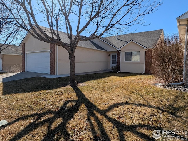 ranch-style home with a garage, brick siding, concrete driveway, a front yard, and stucco siding