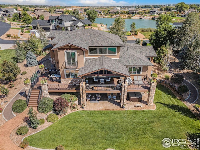 exterior space with a patio, a deck with water view, a yard, stairway, and stucco siding