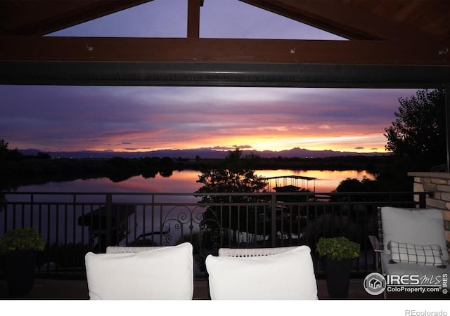 patio terrace at dusk featuring a water view and a balcony