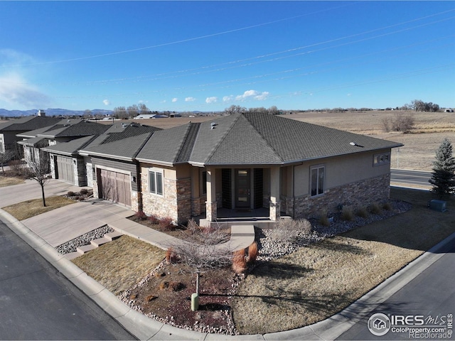 view of front of property with an attached garage, stone siding, concrete driveway, and stucco siding