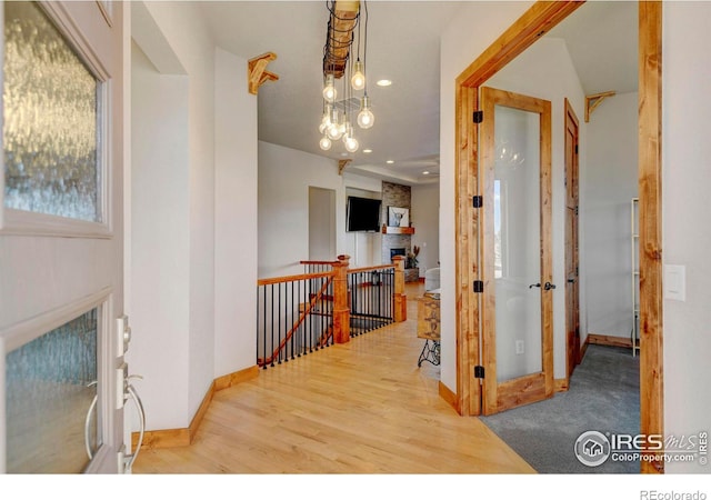 hallway featuring baseboards, recessed lighting, wood finished floors, and an upstairs landing