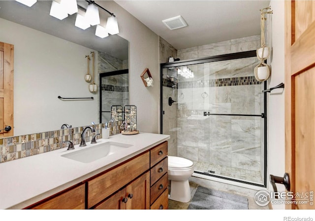 bathroom with visible vents, a stall shower, toilet, and vanity