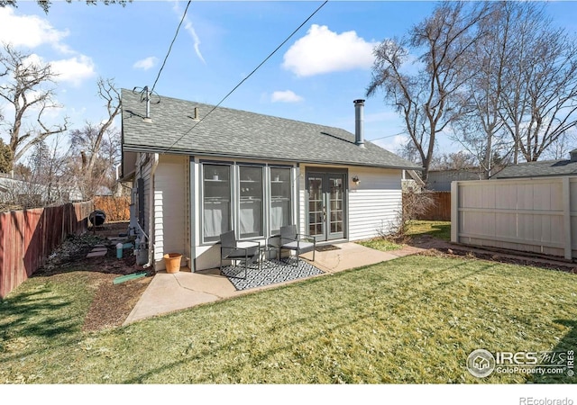 back of property with french doors, a lawn, a shingled roof, and a fenced backyard