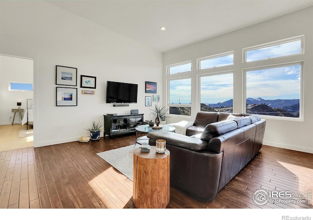 living area with a high ceiling, baseboards, hardwood / wood-style floors, and recessed lighting