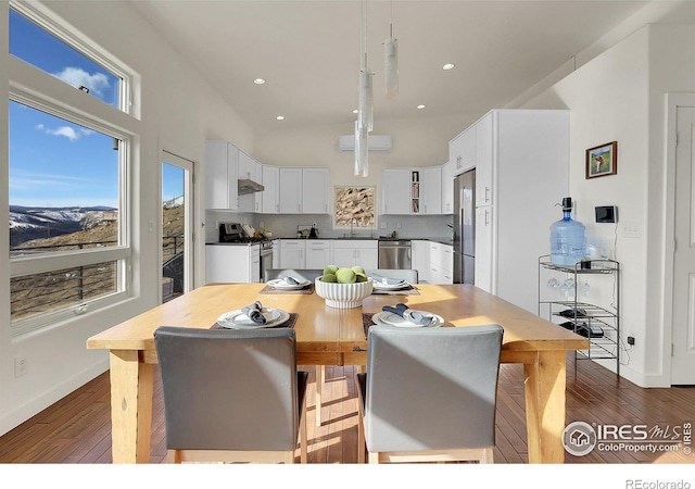 dining space featuring recessed lighting, a towering ceiling, baseboards, and hardwood / wood-style flooring