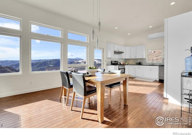 dining area with light wood finished floors, a high ceiling, a wealth of natural light, and recessed lighting