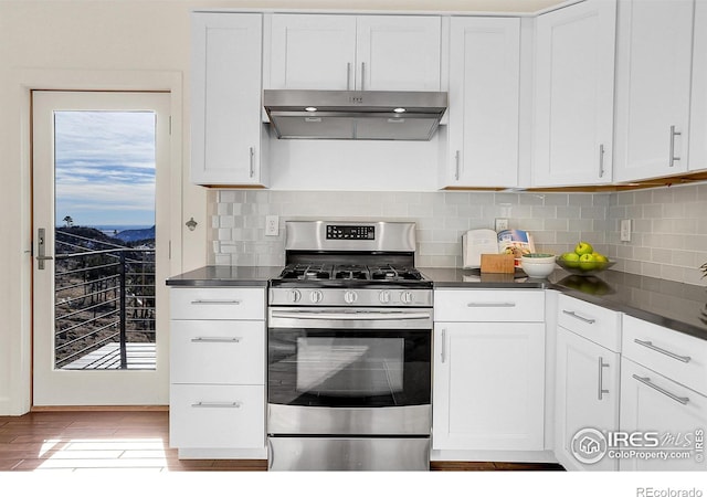 kitchen featuring gas stove, white cabinetry, under cabinet range hood, and dark countertops