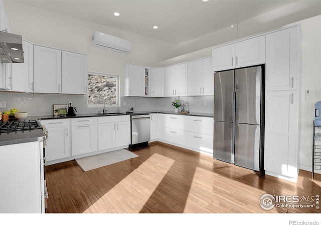 kitchen featuring appliances with stainless steel finishes, dark countertops, an AC wall unit, and wood finished floors