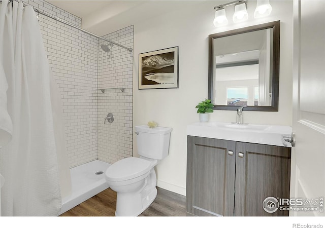 bathroom featuring tiled shower, vanity, toilet, and wood finished floors