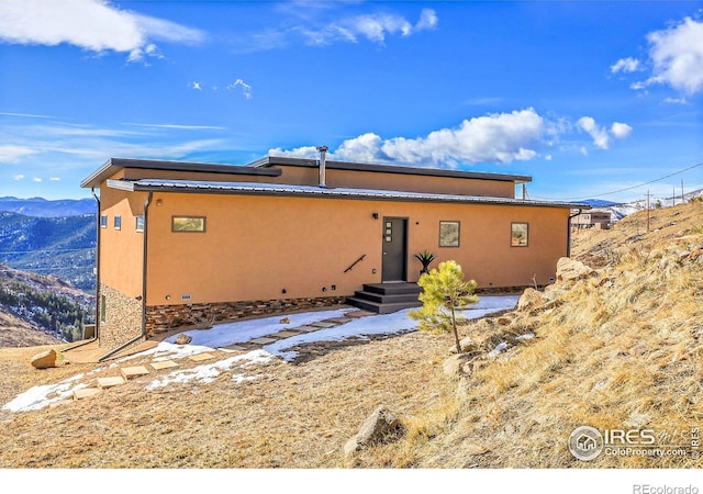 view of front of property with stone siding, a mountain view, and stucco siding