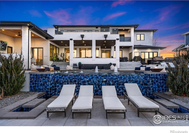 back of house with an outdoor hangout area, a patio area, a balcony, and stucco siding