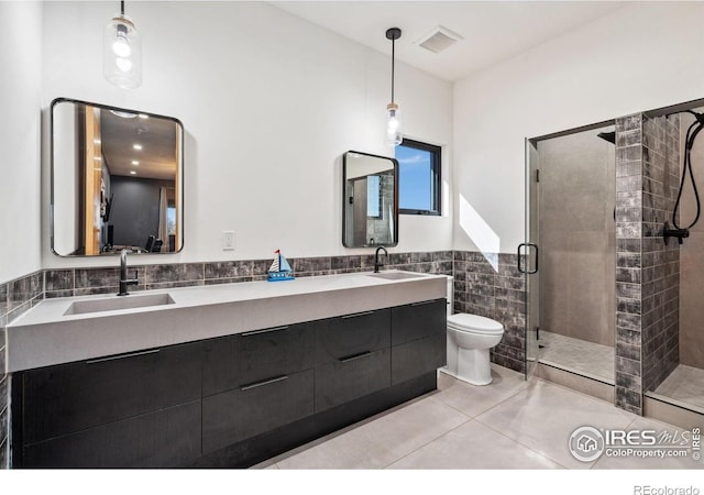 full bath featuring a stall shower, tile patterned flooring, a sink, and tile walls