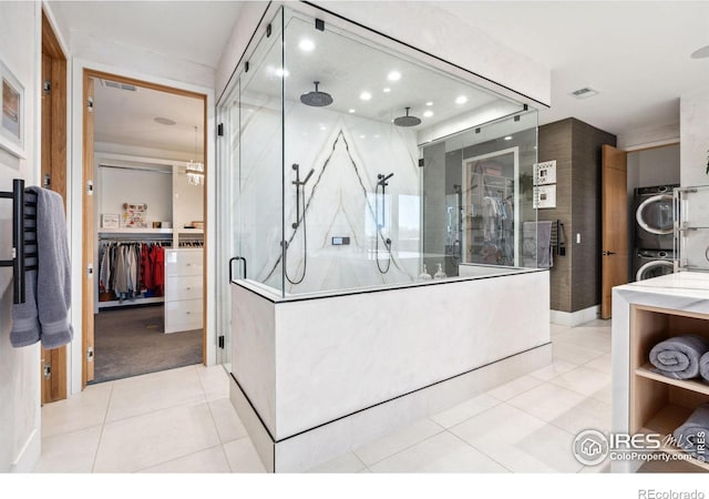 bathroom featuring visible vents, a stall shower, vanity, stacked washing maching and dryer, and tile patterned flooring