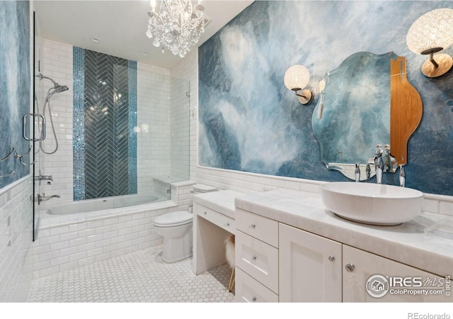 bathroom with toilet, tiled shower / bath combo, tile walls, vanity, and tile patterned floors