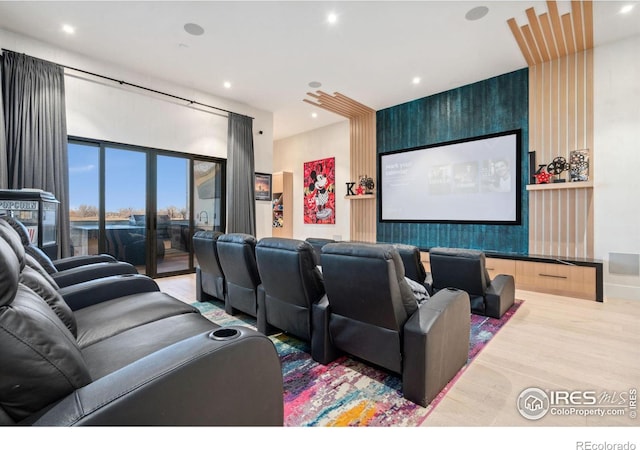 home theater with an accent wall, wood finished floors, and recessed lighting