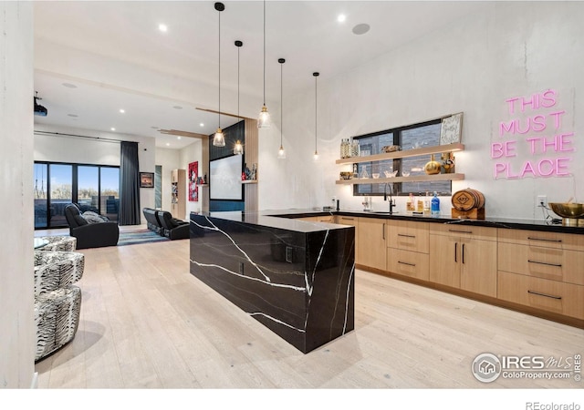 kitchen featuring light wood-style flooring, open shelves, light brown cabinetry, dark countertops, and modern cabinets