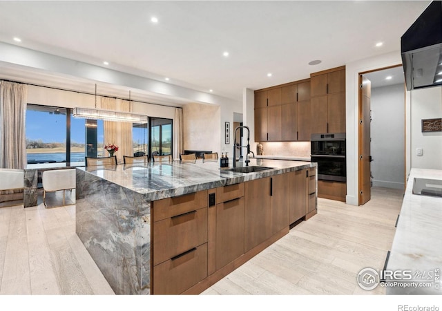 kitchen featuring light wood finished floors, a large island, modern cabinets, and a sink