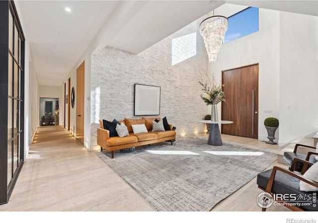 living area with a high ceiling, a chandelier, and wood finished floors