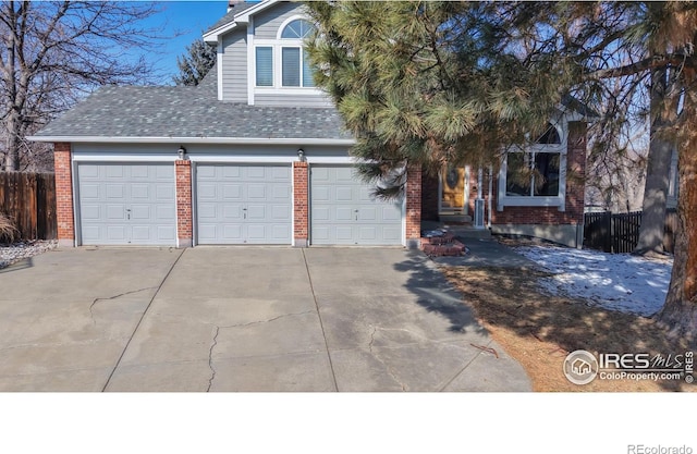 view of front of house featuring a garage, brick siding, fence, and driveway