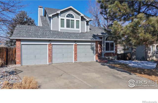 view of front of house featuring brick siding, roof with shingles, a chimney, concrete driveway, and fence