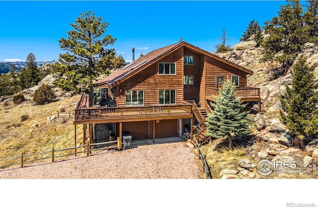 view of front facade with gravel driveway, an attached garage, fence, and a wooden deck