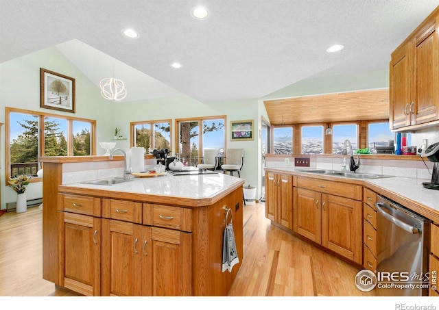 kitchen featuring vaulted ceiling, light countertops, stainless steel dishwasher, and a sink