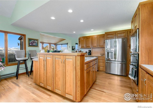 kitchen featuring stainless steel appliances, a wealth of natural light, light countertops, and light wood-style flooring