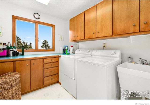 clothes washing area with cabinet space, separate washer and dryer, a sink, and light floors