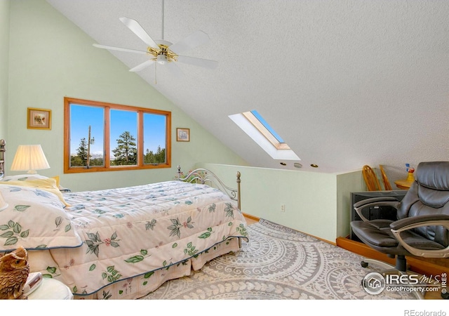 bedroom featuring a textured ceiling, vaulted ceiling with skylight, ceiling fan, and baseboards