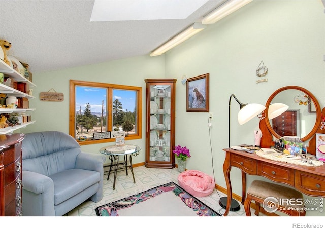 sitting room featuring vaulted ceiling with skylight, a textured ceiling, and baseboards