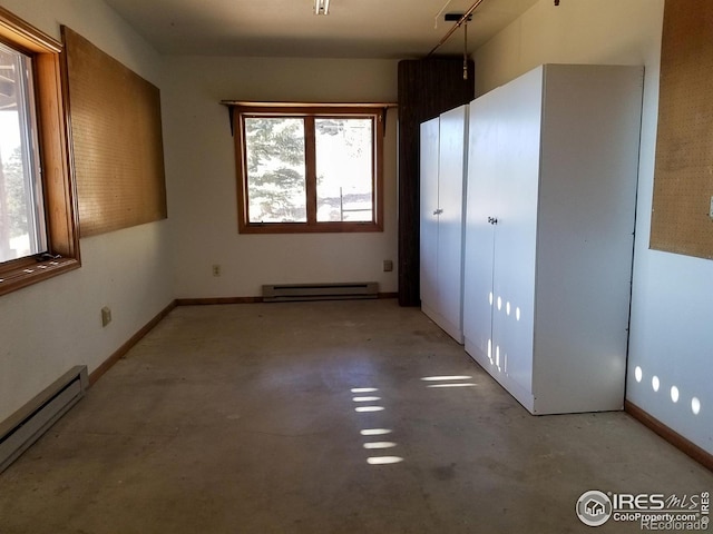 unfurnished bedroom featuring a baseboard heating unit, concrete flooring, and multiple windows