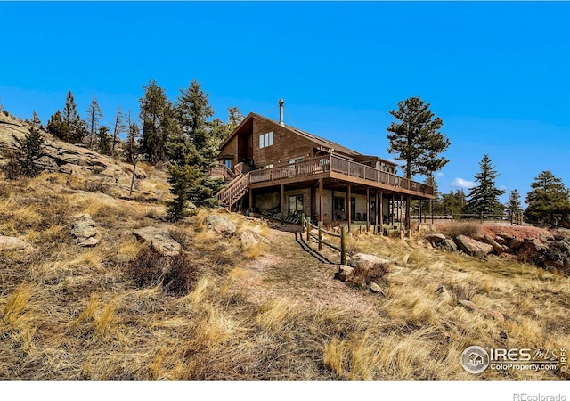 rear view of property featuring a wooden deck and stairs