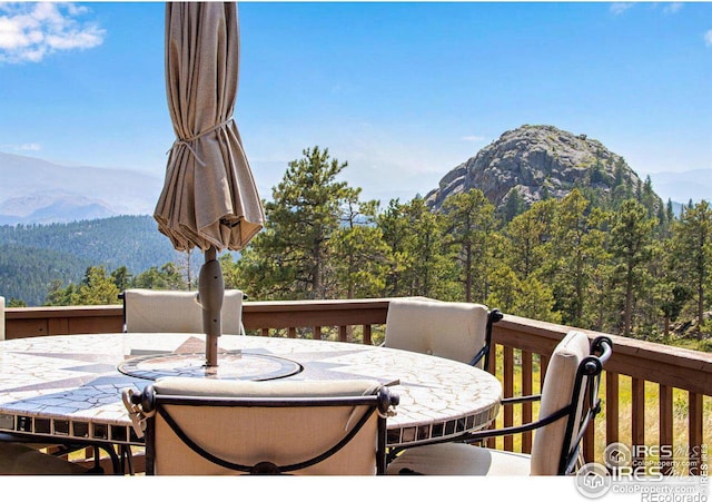 131 Mount Apiatan Ct, Livermore, CO 80536 - wooden deck featuring outdoor dining space, a mountain view, and a wooded view