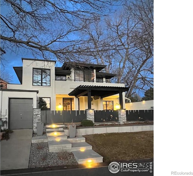 view of front of property featuring a garage, a fenced front yard, concrete driveway, and stucco siding