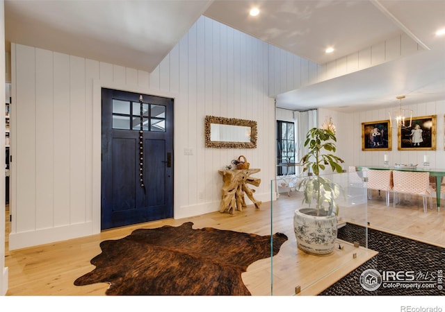 foyer featuring vaulted ceiling, wood finished floors, and a notable chandelier