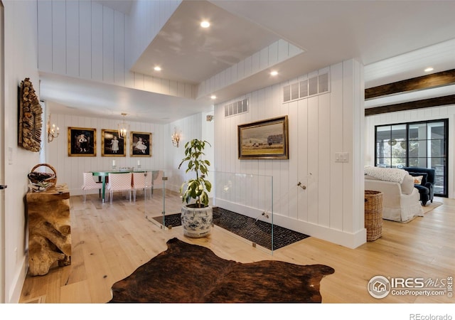 living room featuring light wood finished floors, visible vents, and beamed ceiling