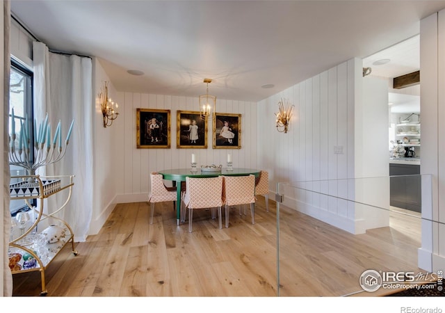 dining area featuring a chandelier, baseboards, and light wood finished floors