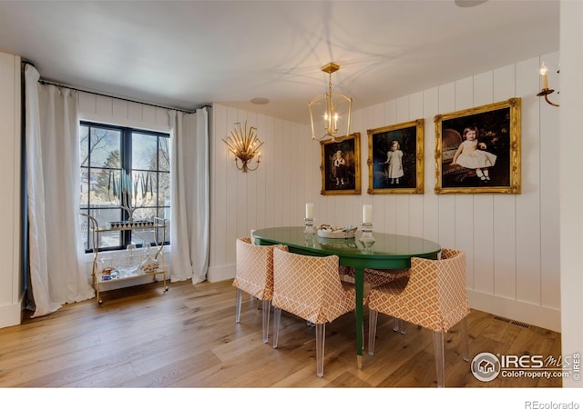 dining space with a chandelier, light wood-type flooring, visible vents, and baseboards