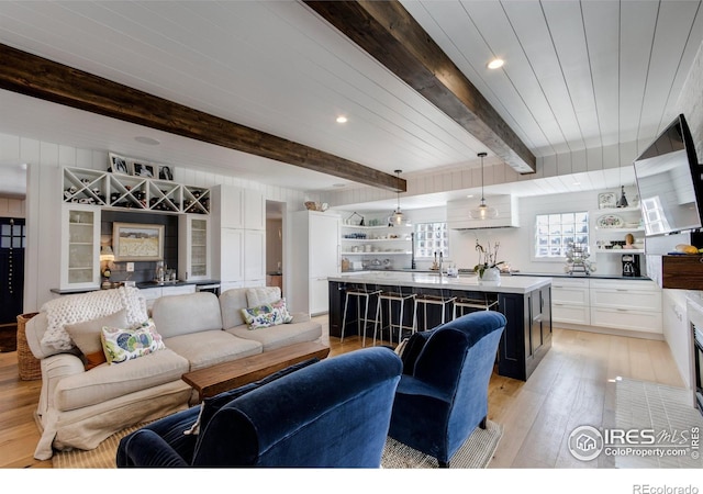 living area with beamed ceiling, indoor wet bar, light wood-style flooring, and recessed lighting