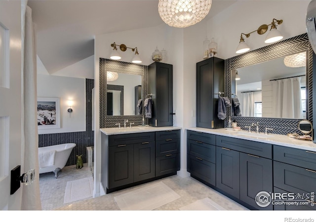 bathroom featuring a freestanding bath, two vanities, a sink, and tile patterned flooring