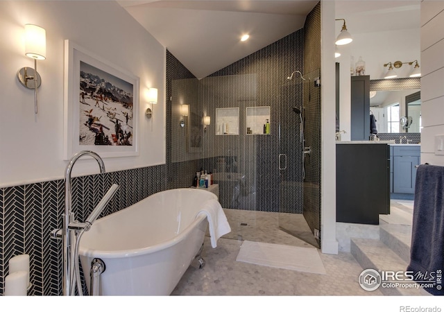 bathroom featuring tile walls, a stall shower, vaulted ceiling, vanity, and a freestanding tub