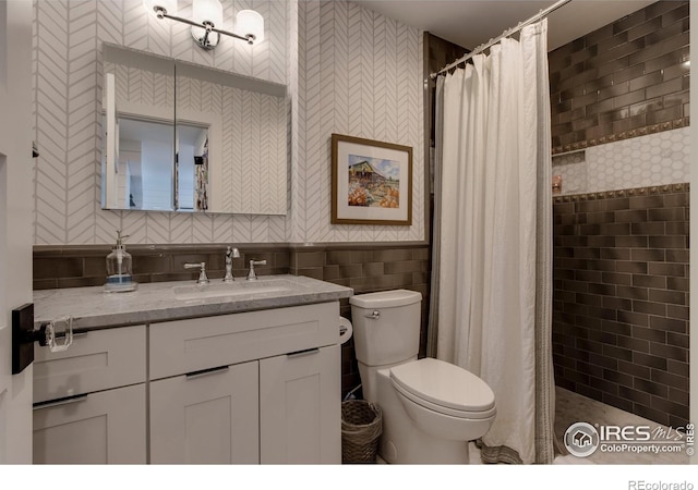 full bathroom featuring toilet, a tile shower, tile walls, and vanity