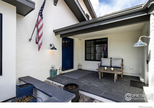 property entrance with brick siding and a patio area