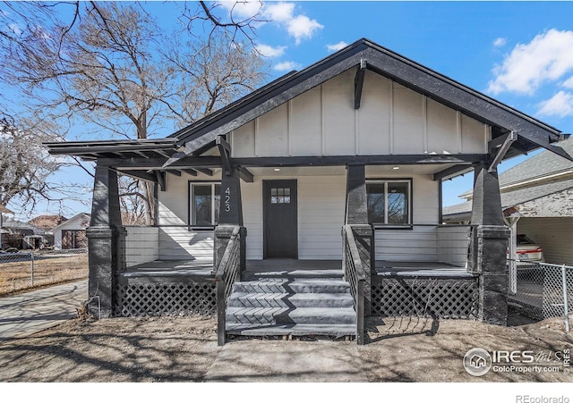 view of front facade with a porch, board and batten siding, and fence